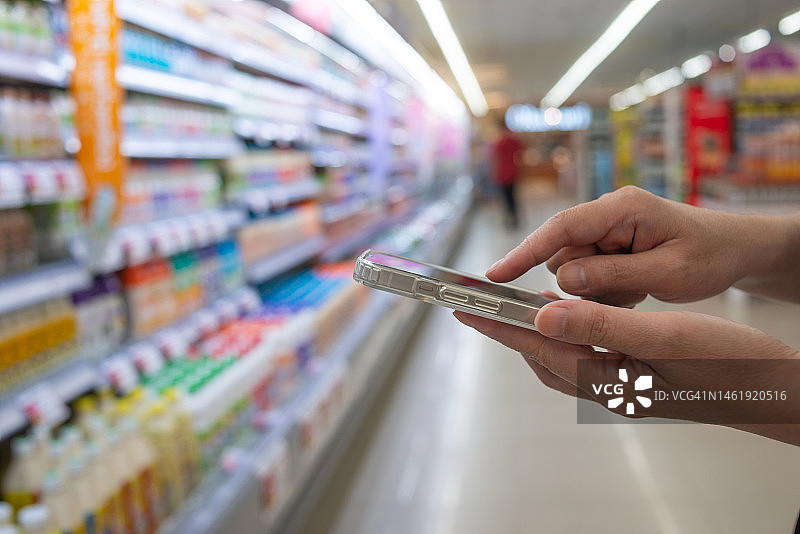 女人在百货商店内使用手机，用于支付和记账图片素材
