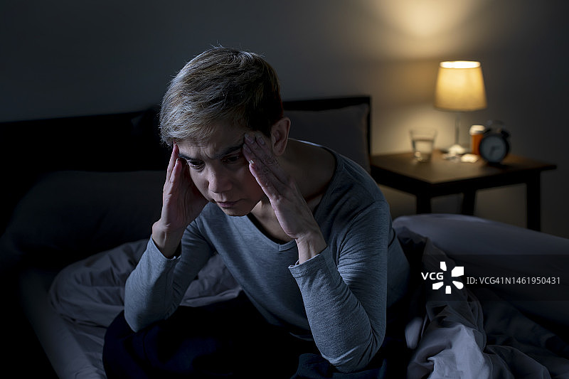 抑郁的亚洲老年妇女坐在床上无法入睡，因为失眠图片素材