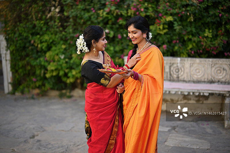 两位身穿纱丽的印度女性手持祭祀盘交谈图片素材