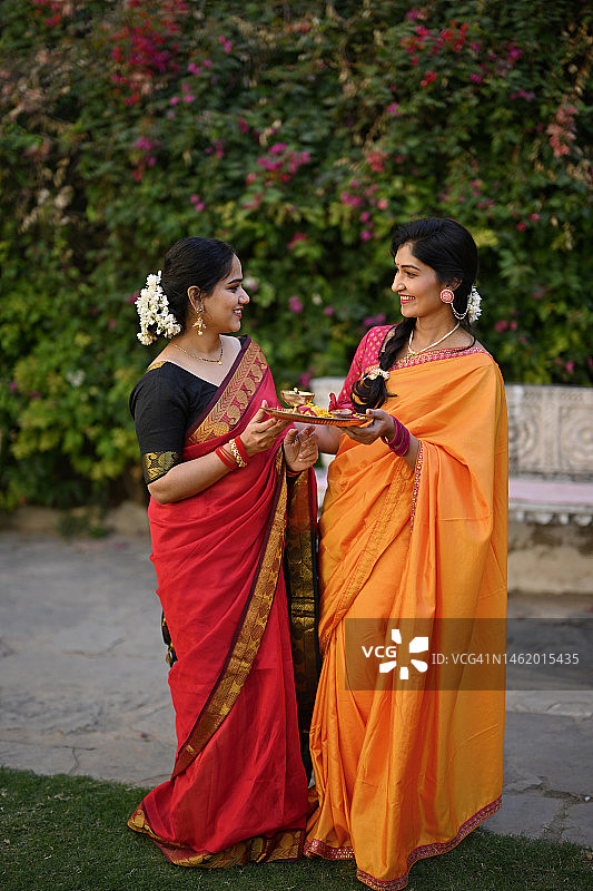 两位身穿纱丽的印度女性手持祭祀盘交谈图片素材