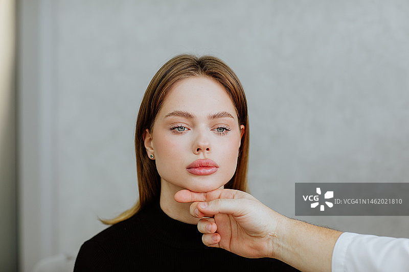在诊室里，医生用手触摸年轻女子的脸图片素材