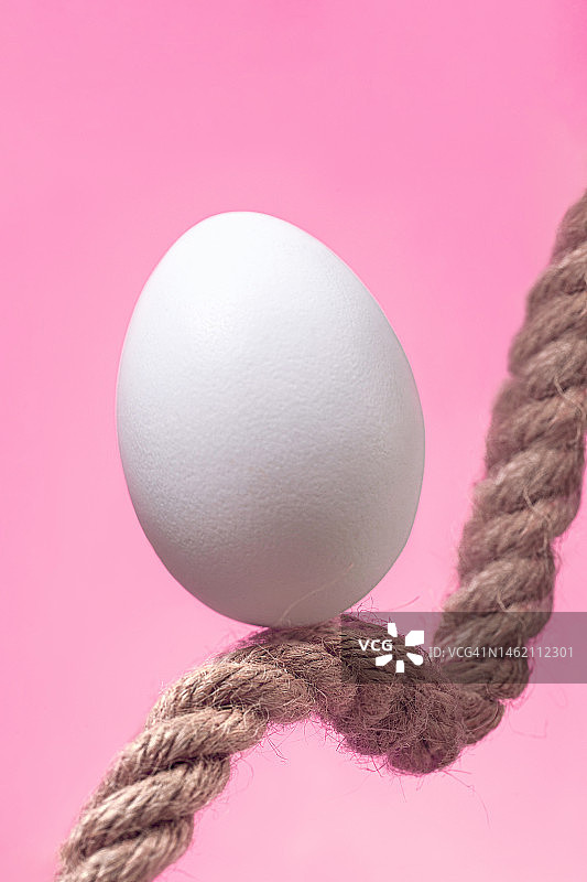 粉红色背景麻绳上的白色复活节彩蛋，复活节简约概念图片素材