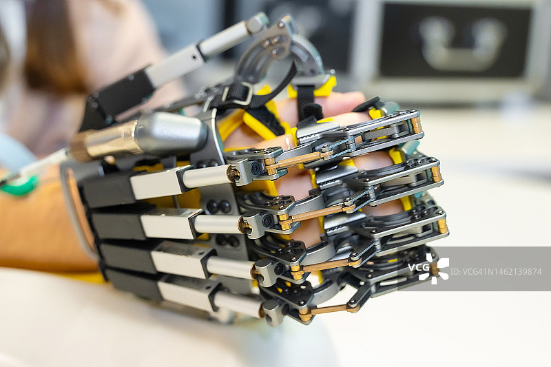 现代医院的机械外骨骼手部理疗：康复训练中机器人手臂的细节。科学家、工程师和理疗康复医生使用平板电脑辅助图片素材
