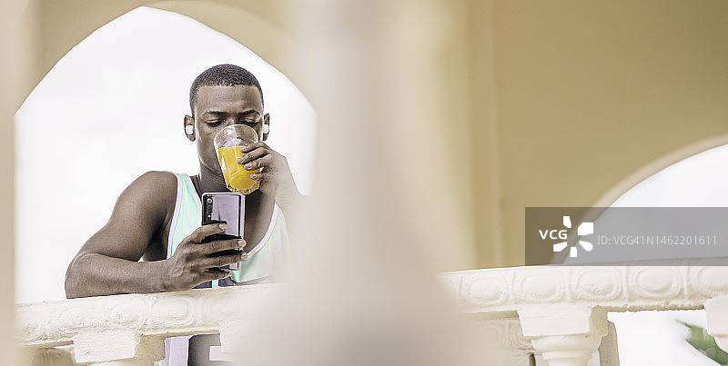 喝果汁和使用手机的非裔美国男人图片素材