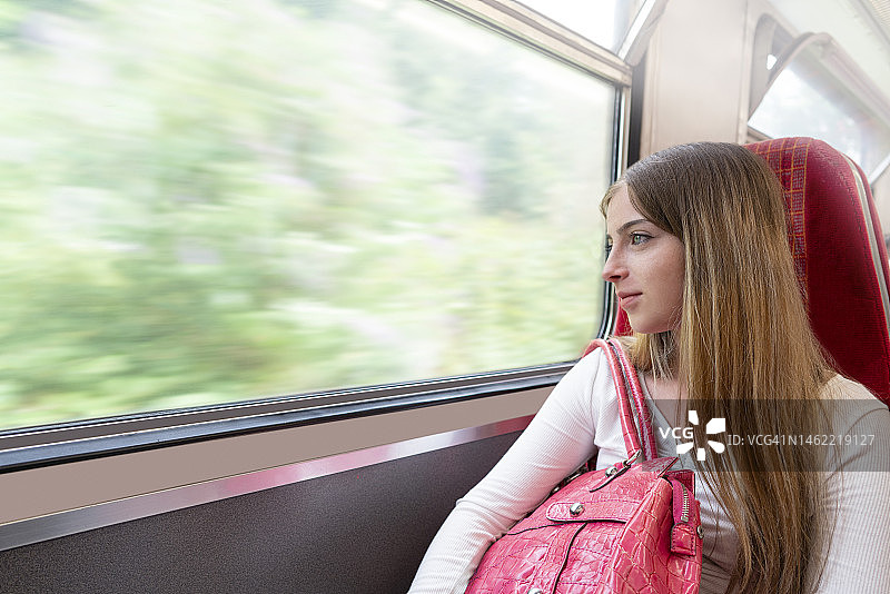 在英格兰火车上看向窗外的年轻金发女乘客图片素材