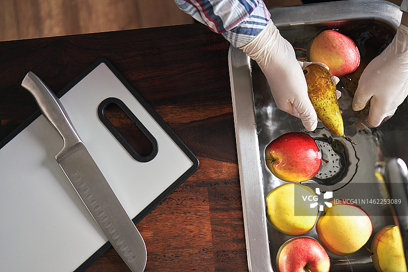 食品安全：戴食品手套在水槽中清洗苹果和梨图片素材