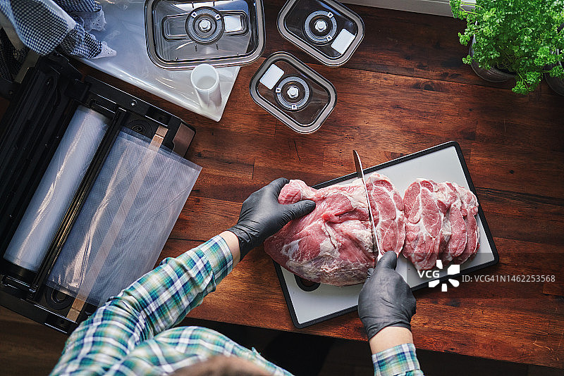 食品安全：戴食品手套在塑料砧板上切猪排图片素材