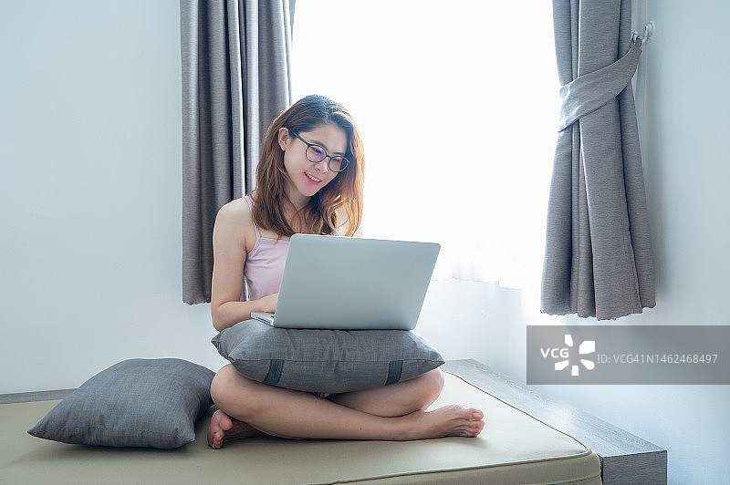 在卧室用笔记本电脑工作的年轻亚洲女性肖像图片素材