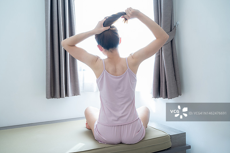 女子在卧室里扎头发的背影图片素材
