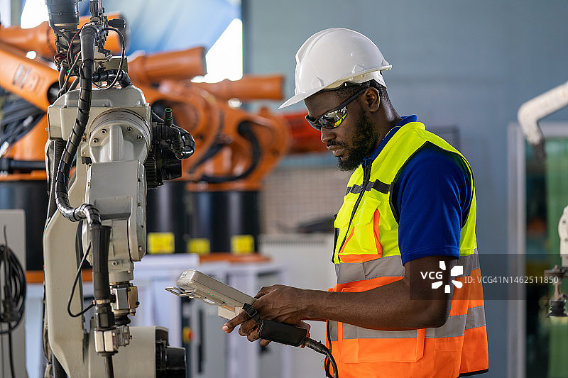 工程师在智能工厂检查和控制自动化机器人手臂图片素材
