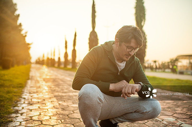 跑步前后男子查看健身追踪器上的数据图片素材