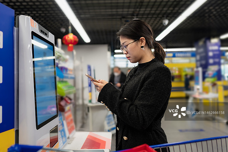 亚洲女人在超市使用无人扫码结账图片素材