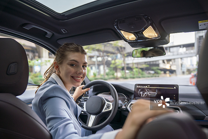 看着后视镜停车的年轻微笑女人图片素材