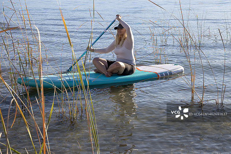 在平静的湖面上划桨的中年妇女图片素材
