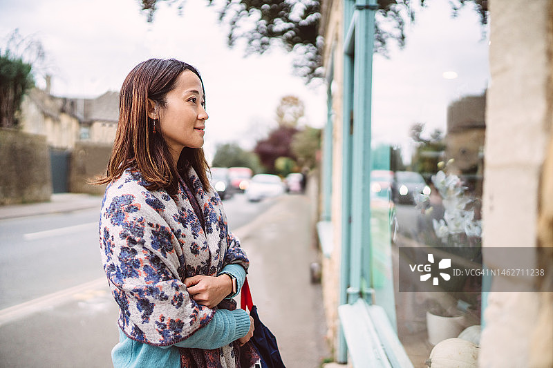 年轻漂亮的亚洲女游客在城镇的主要街道的餐厅外看菜单图片素材