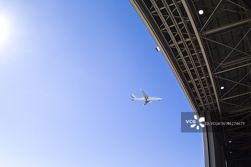 喷气式客机飞过机场敞开的机库大门图片素材