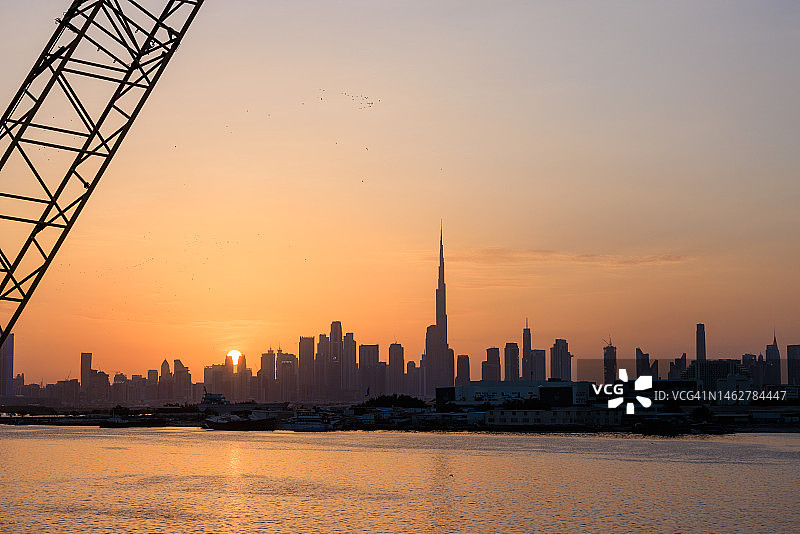 日落时分阴天下的迪拜城市天际线湖畔风光图片素材