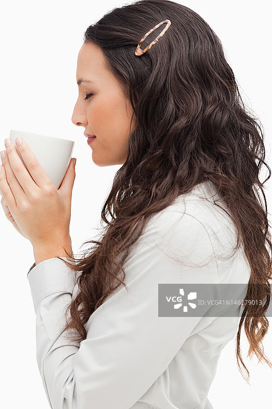 棕发女子闻着热咖啡的侧影图片素材
