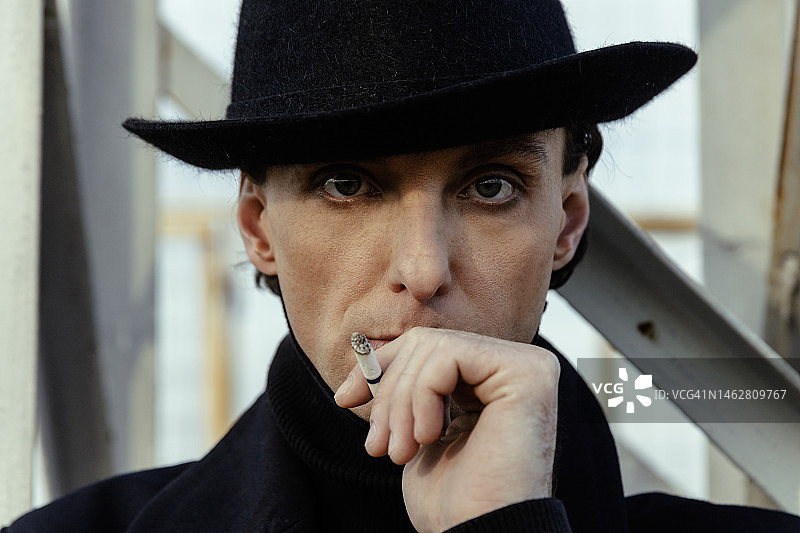 戴着软呢帽的时尚成年男人在吸烟图片素材