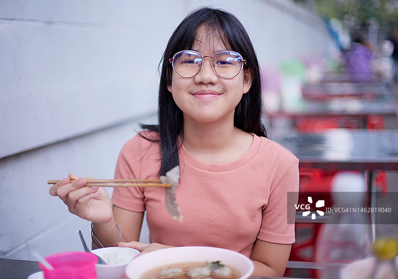 女孩在街头市场享用拉面图片素材