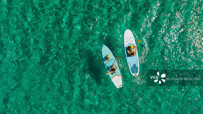 年轻的家庭在海上玩桨板冲浪图片素材