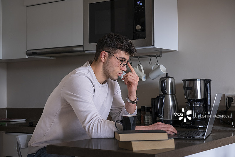 男人在厨房看笔记本电脑屏幕图片素材