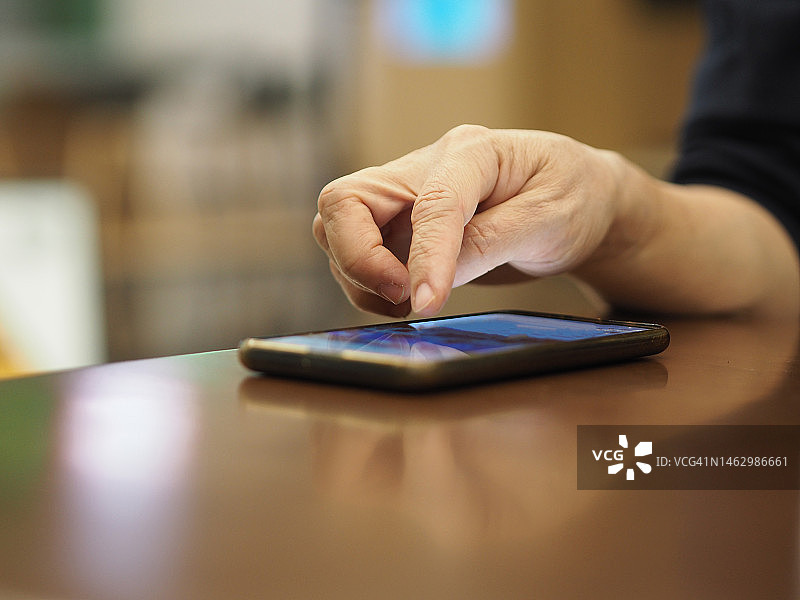 女人用智能手机放在木桌上图片素材