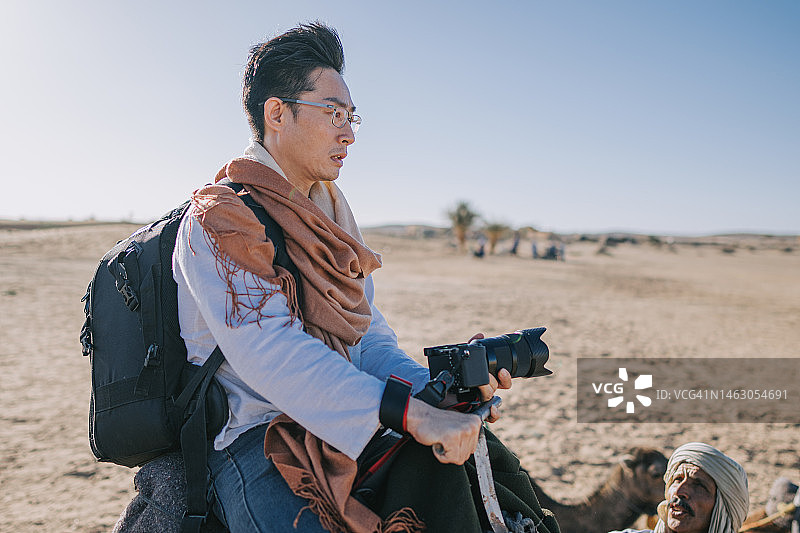 中国游客骑着单峰骆驼穿越摩洛哥撒哈拉沙漠图片素材