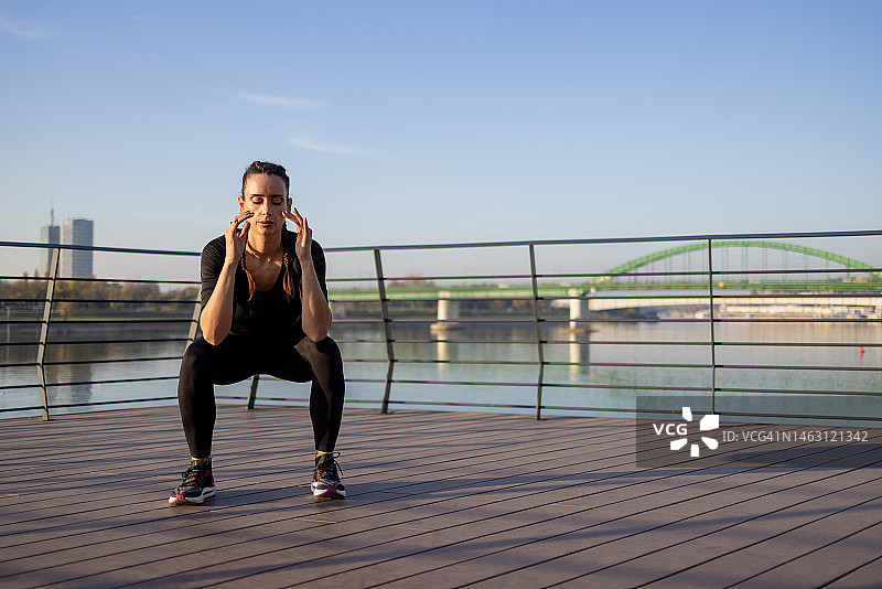 在河边做深蹲的30多岁白人女性图片素材
