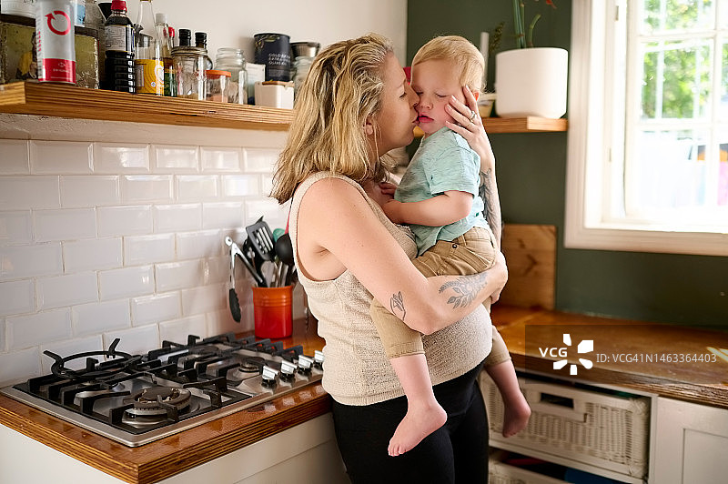 怀孕的母亲与孩子在厨房拥抱图片素材