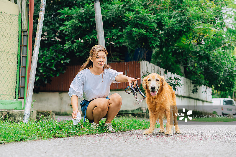 女人在路边清理她的狗的粪便图片素材
