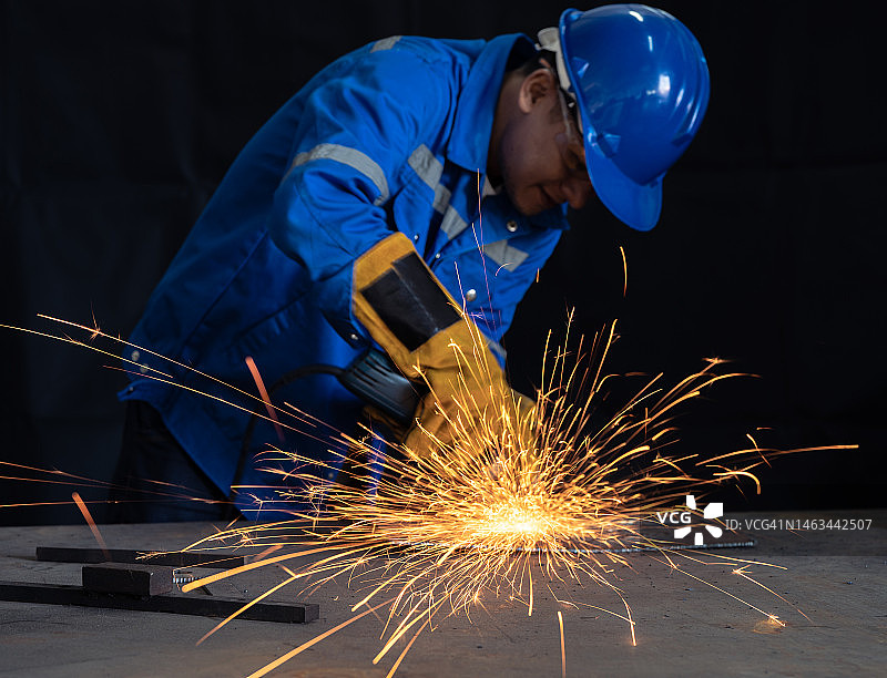 重工业工人用角磨机切割钢材图片素材