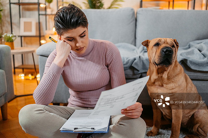 年轻女人和她的狗在家查看财务状况图片素材