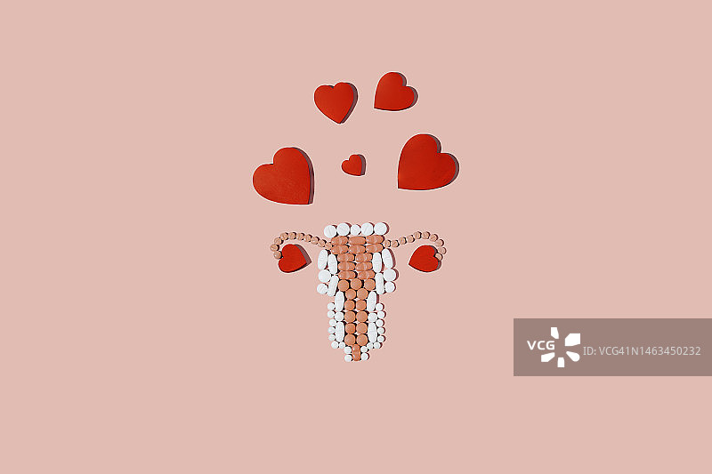 粉色背景上女性生殖系统形状的药丸（心形代替卵子）图片素材