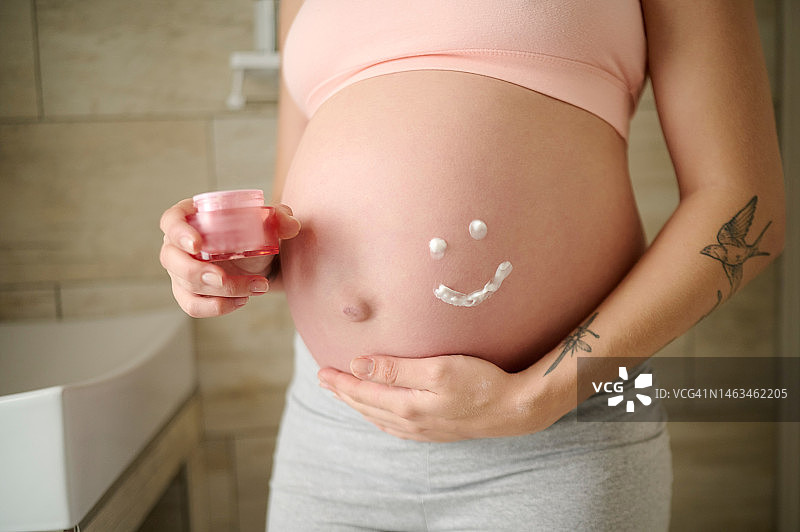孕妇在浴室的皮肤护理、乳霜和胃部，用于美容、妊娠纹和化妆品。微笑、产品和怀孕，母亲在家使用乳液进行按摩、放松和防晒图片素材