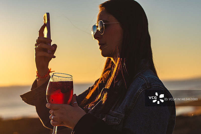 女人拿着饮料拍摄日落图片素材