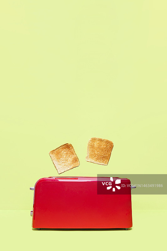 绿色背景上的红色烤面包机和两片新鲜吐司图片素材