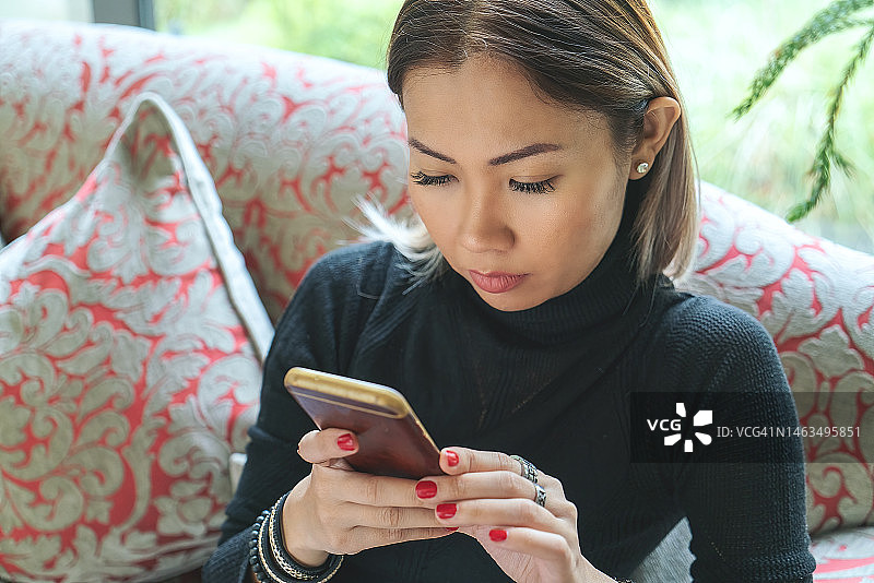 在酒店大堂使用手机的女人图片素材