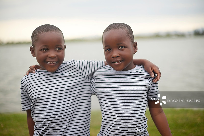 拥抱：湖边度假的非洲双胞胎兄弟图片素材