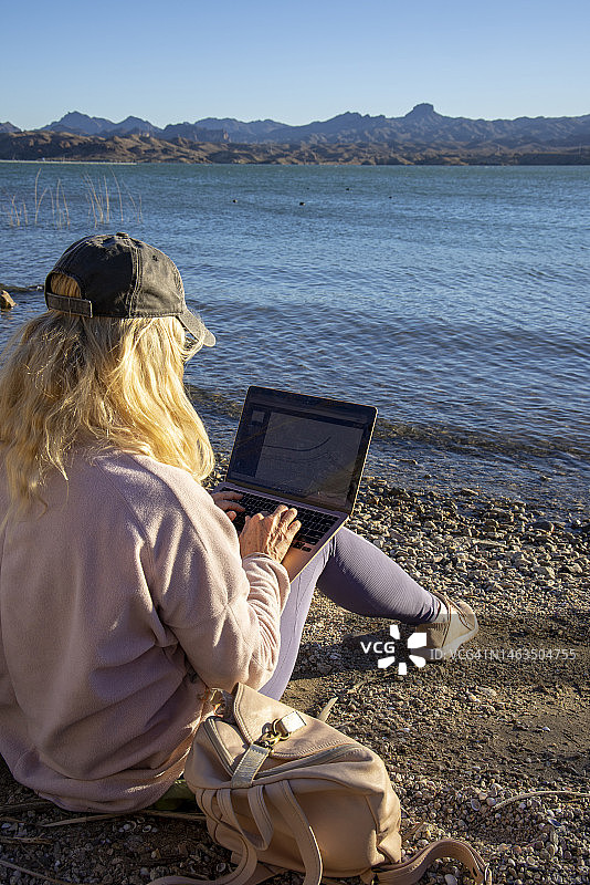 中年妇女在湖边使用笔记本电脑图片素材