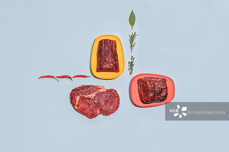 生牛排肉，盘中香料，蓝色背景图片素材
