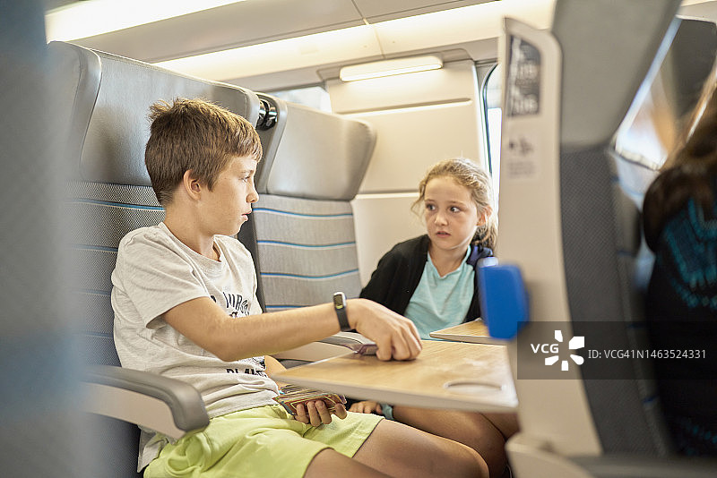 一个棕色头发的白人男孩和一个类似描述的女孩坐在火车里图片素材