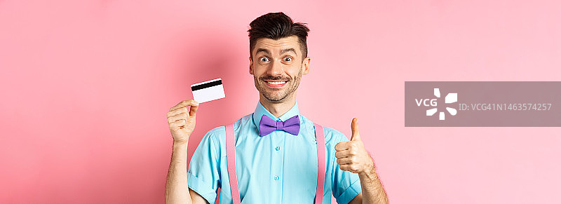 系着领结，竖起大拇指，拿着塑料信用卡的快乐男人，点赞图片素材