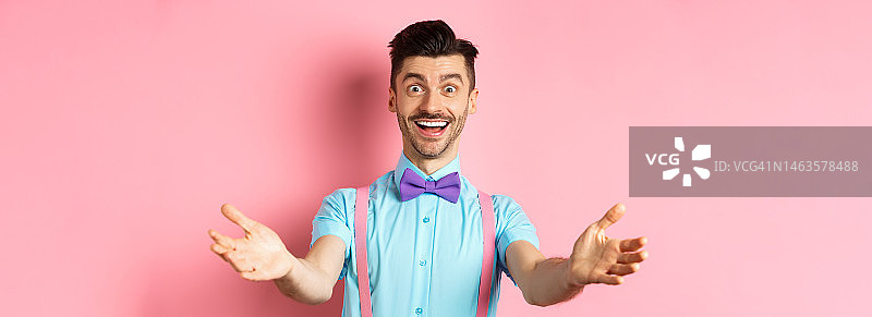 快乐英俊的男人系着领结，张开双臂表示热烈欢迎图片素材