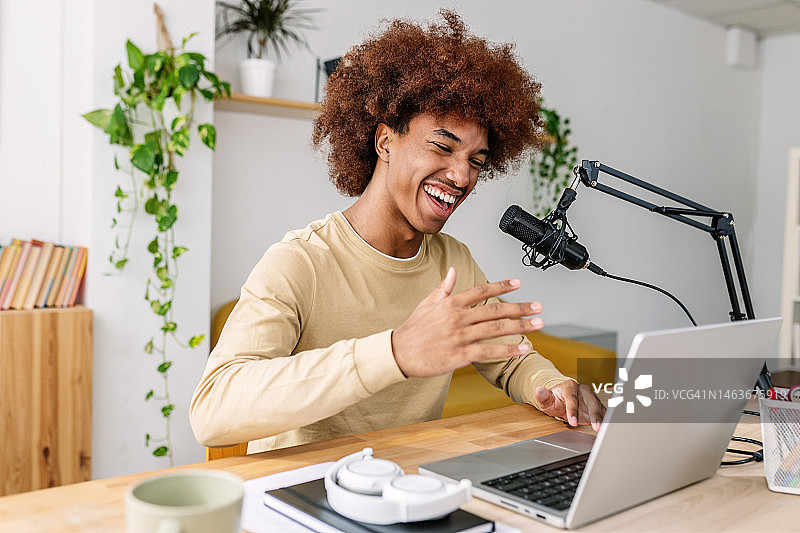微笑的拉丁美洲年轻内容创作者在家中舒适的录音棚录制播客图片素材