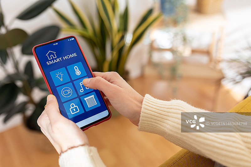 年轻女子在沙发上使用IOT智能家居App的特写镜头图片素材