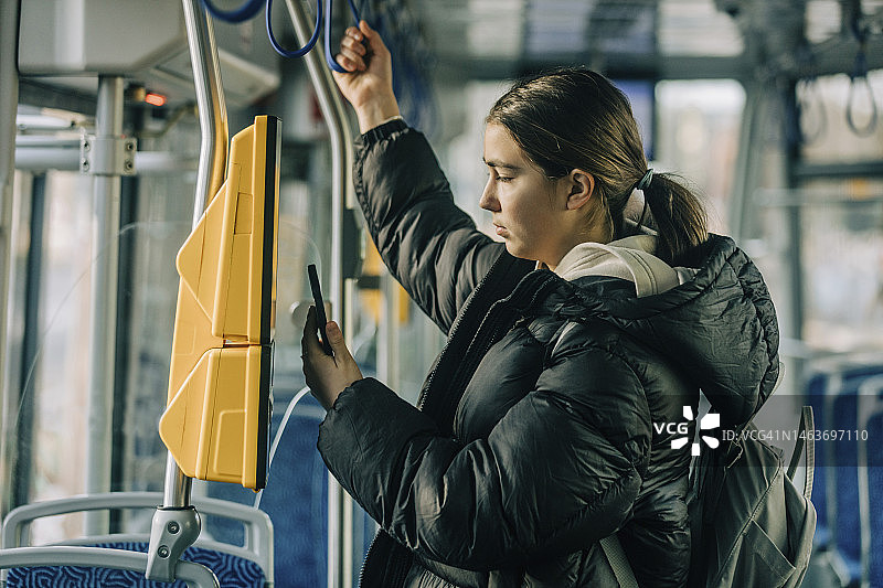少女在有轨电车上用智能手机购票图片素材