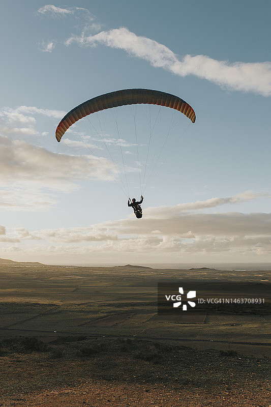 日落时分在多云天空下滑翔的男人图片素材
