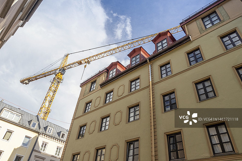 德国巴伐利亚州慕尼黑公寓楼上方的工业起重机图片素材
