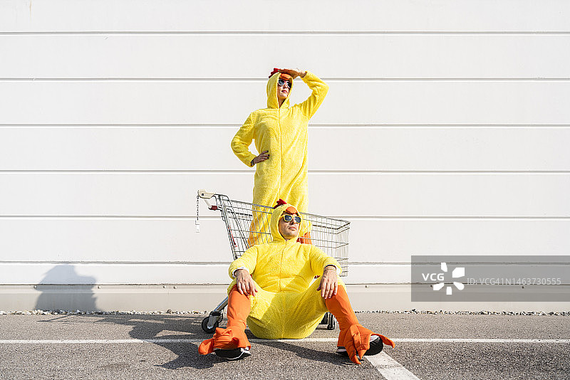 站在穿着黄色小鸡服装的女人（购物）购物车前，遮住眼睛的男人图片素材